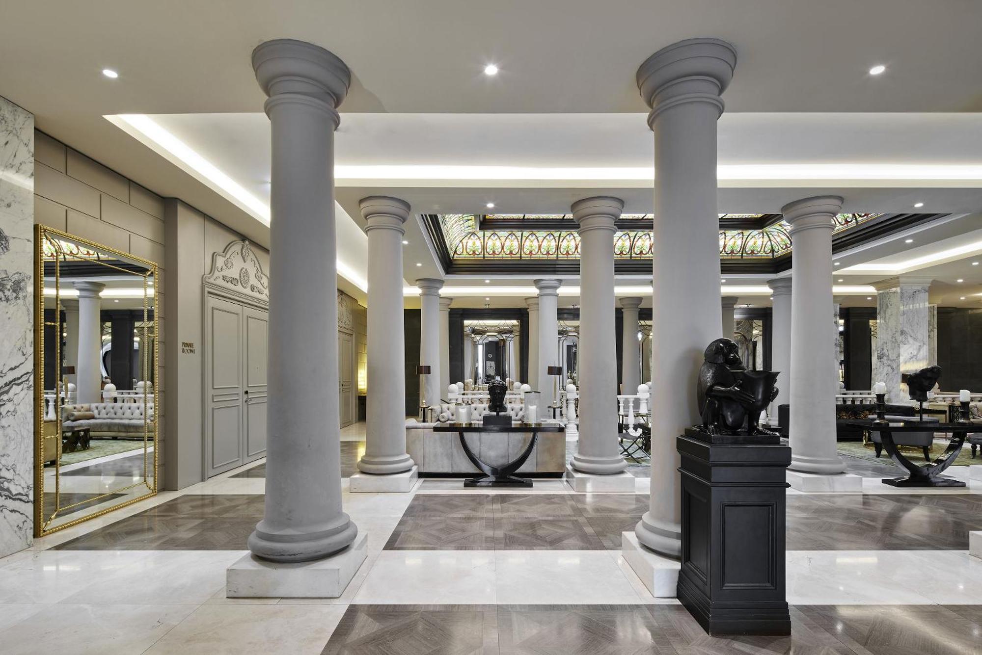 柏林御林广场泰坦尼克酒店 外观 照片 The photo shows an elegant interior space featuring several tall, decorative columns. The flooring is a mix of stone or marble tiles, showcasing a sophisticated design. There are mirrors and other classic architectural details on the walls, contribut